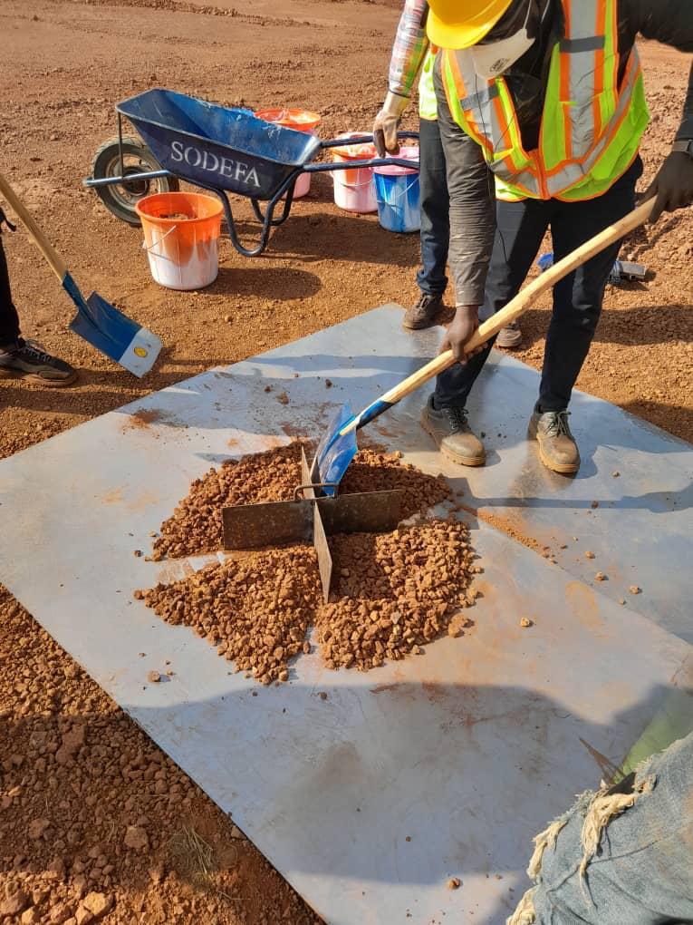 Person shoveling gravel onto a white geotextile fabric at a construction site.