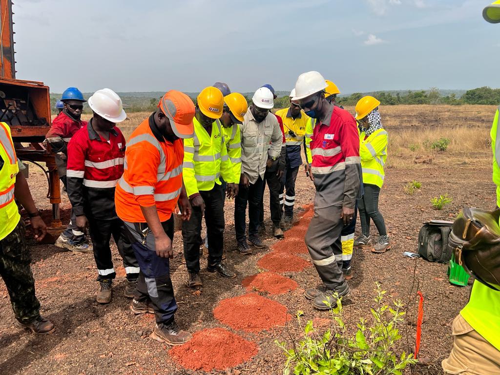 Workers in safety gear inspecting soil on a construction site.